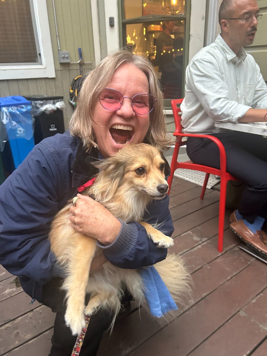 Katia laughing while holding a new dog friend