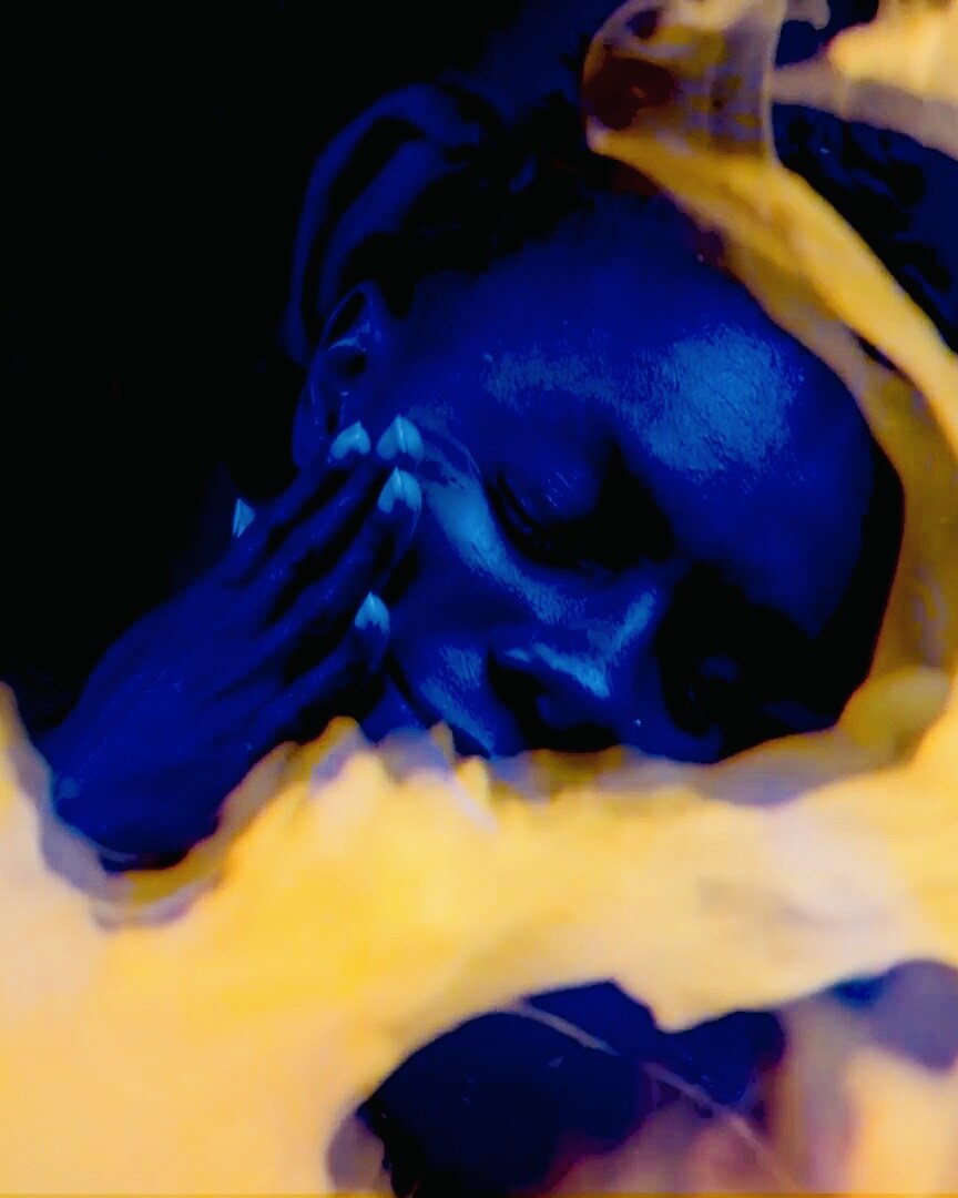 Courtney Desiree Morris in blue light surrounded by golden translucent forms